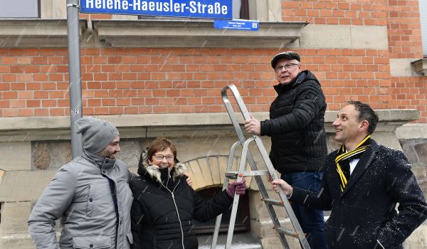 Vier Personen bringen ein Schild an.