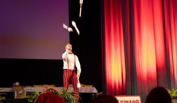 Ein Mann jongliert mit Keulen auf einer Bühne.