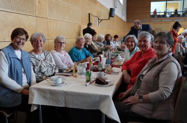 Frauen sitzen an gedeckten Tischen.