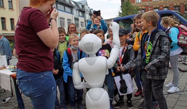 Kinder stehen vor einem weißen Roboter.