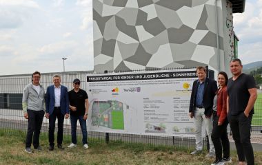 Sechs Personen stehen neben einem Schild mit der Aufschrift: Freizeitareal für Kinder und Jugendliche Sonneberg.