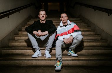 Zwei junge Männer sitzen auf einer Treppe.