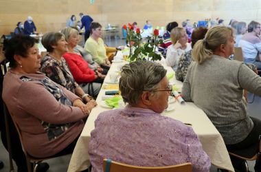 Frauen sitzen an gedeckten Kaffeetischen.