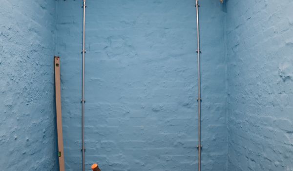 An einer blauen Wand sind Rohre verlegt.