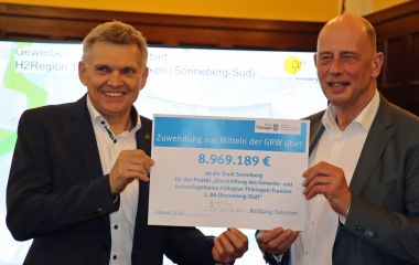 Zwei Männer halten gemeinsam einen Zuwendungsbescheid.