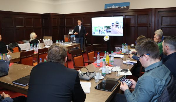 Mehrere Personen sitzen an einem u-förmigen Tisch.