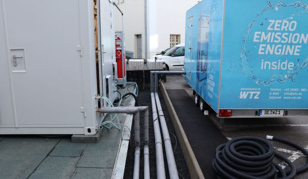 Zwischen einem Container und einem Anhenger sind Rohre verlegt.