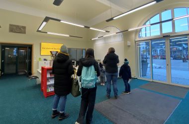 Am Bibliotheksschalter steht einen Menschenschlange.