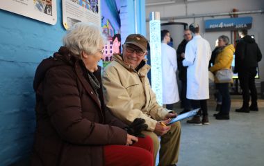 Zwei Besucher sitzen auf einer Bank bei der Ausstellung.