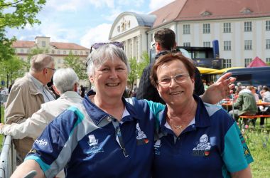 Zwei Helferinnen in blauen Trikots. Im Hintergrund ist das Rathaus der Stadt Sonneberg zu sehen.