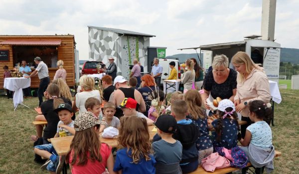 Kinder sitzen auf Bänken vor dem geplanten Freizeitareal.