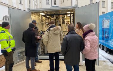 Interessierte Gäste schauen sich eine technische Anlage in einem Container an.