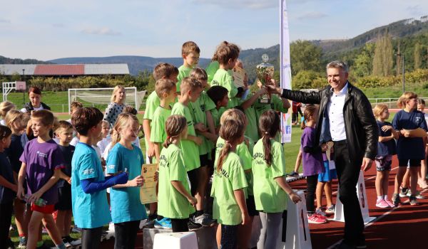 Kinder stehen auf einem Podest. Ein Mann überreicht ihnen einen Pokal. Es ist der Bürgemeister Dr. Heiko Voigt.