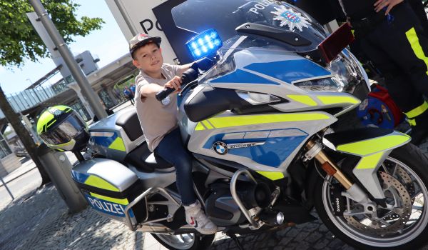 Ein Junge sitzt auf einem Polizei-Motorrad.