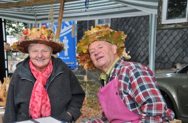 Eine Frau und ein Mann tragen einen Hut, der mit Blättern geschmückt ist.