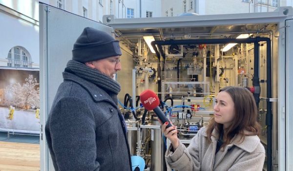 Eine Frau interviewt einen Mann vor einen Container.