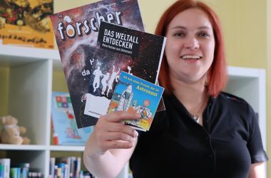 Eine Frau hält Sach- und Kinderbücher in einer Hand.