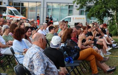Menschen sitzen vor einer Bühne und klatschen.
