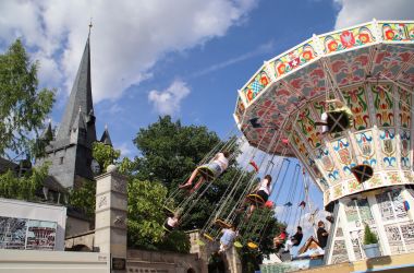 Ein Kettenflieger steht neben einer Kirche.
