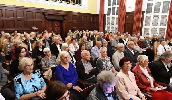 Viele Menschen sitzen in Stuhlreihen in einem Saal.