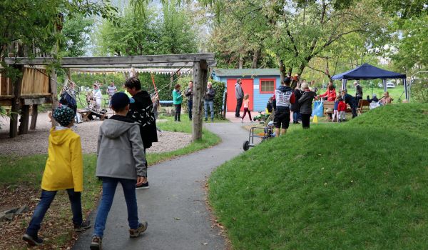Kinder auf einem Spielplatz, umgeben von grünen Bäumen.
