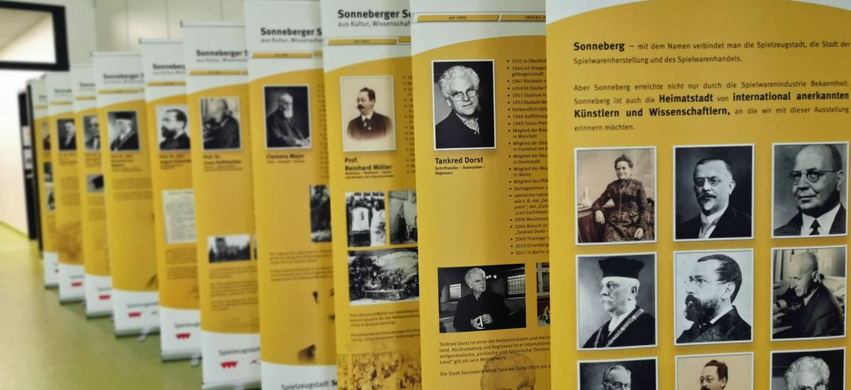Verschiedene Roll-up Aufsteller stehen hintereinader in einer Reihe. Sie zeigen Bilder und Texte zu historischen Personen.