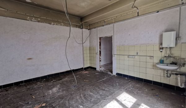 Eine Baustelle in einem Gebäude. Kabel hängen von der Decke.