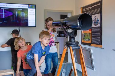 Kinder schauen durch ein Fernrohr.