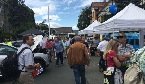 Viele Menschen stehen auf einer Straße. Links und rechts sind  Verkaufsstände aufgebaut.