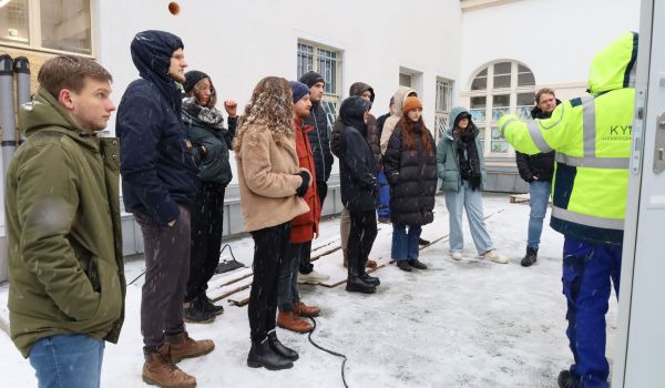 Ein Mann in gelber Warnjacke erklärt Interessierten eine teschnische Anlage.