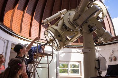 Kinder schauen durch ein Teleksop in der Kuppel.
