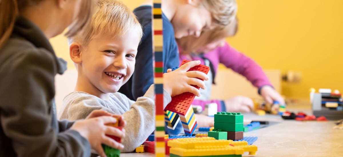 Kinder sitzen an einem Tisch und spielen.
