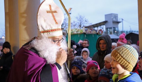 Ein Mann in Nikolaus-Kostüm mit goldenem Zepter. Um ihn herum stehen viele Kinder.