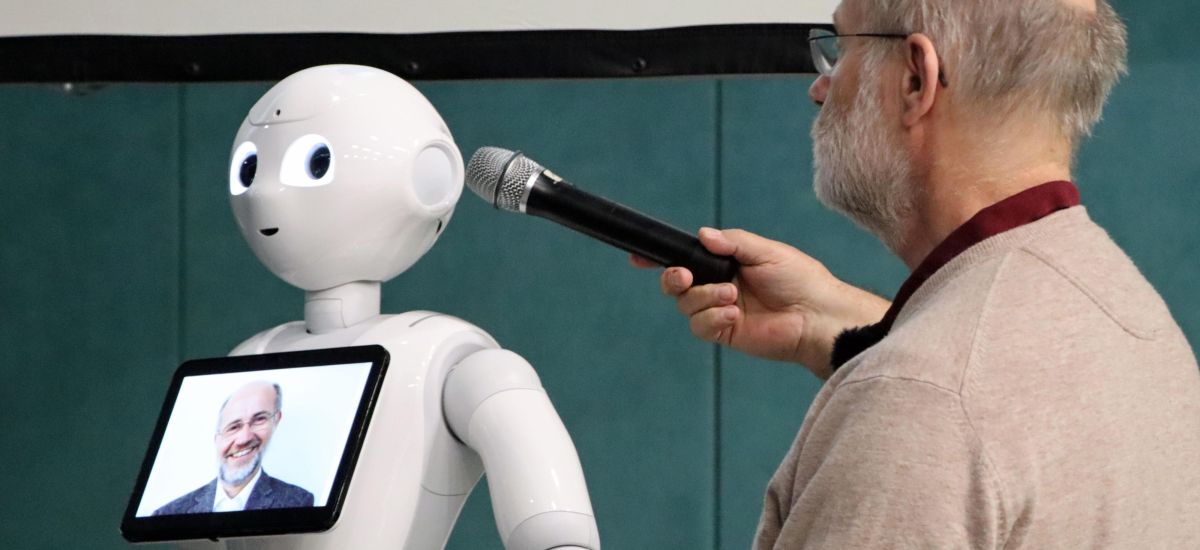 Ein Mann hält ein Mikrofon zu einem Roboter.