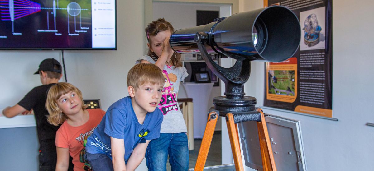 Kinder schauen durch ein Fernrohr.