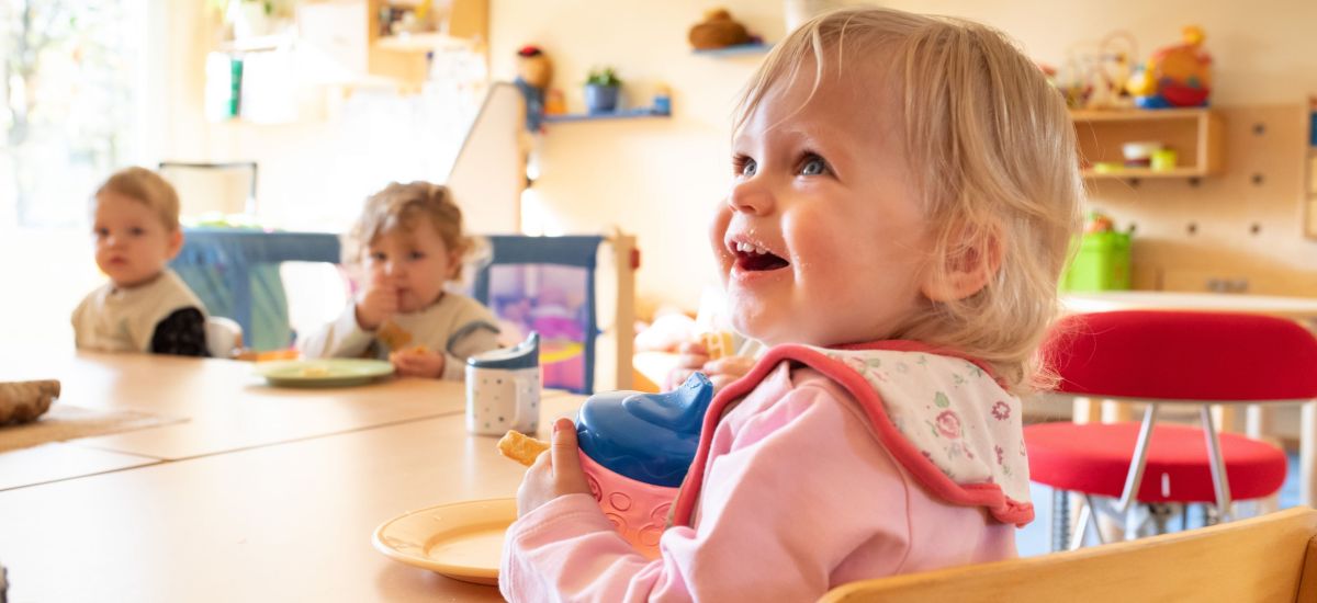 Kinder sitzen im Kindergarten an einem Tisch und Essen.