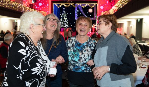 Vier Frauen stehen zusammen und lachen.