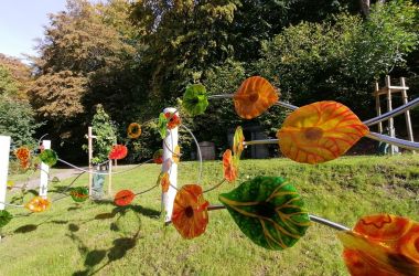 Eine Art Metallzaun mit bunten Blättern daran.