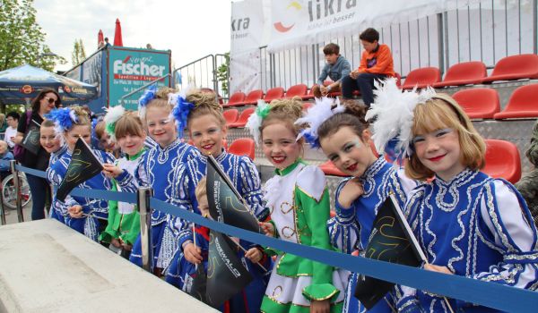 Kinder als Tanzmariechen gekleidet stehen auf einer Tribühne.