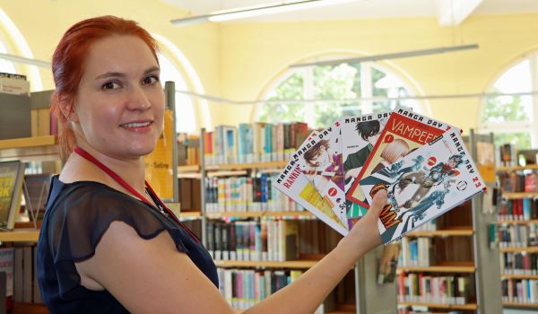 Eine Frau hält verschiedene Mangas in der Hand.