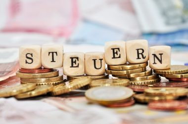 Das Wort Steuern steht auf Würfeln. Darunter liegt Geld.
