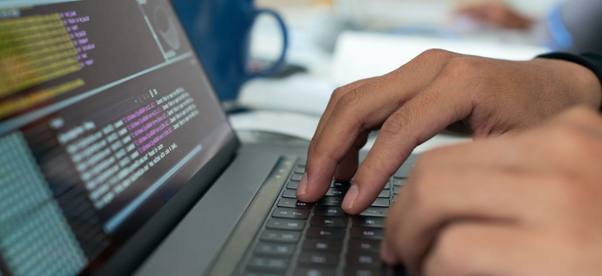 Hände schreiben auf einem Laptop.