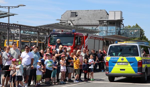 Viele Menschen stehen hinter einer Absperrung vor dem Bahnhof.