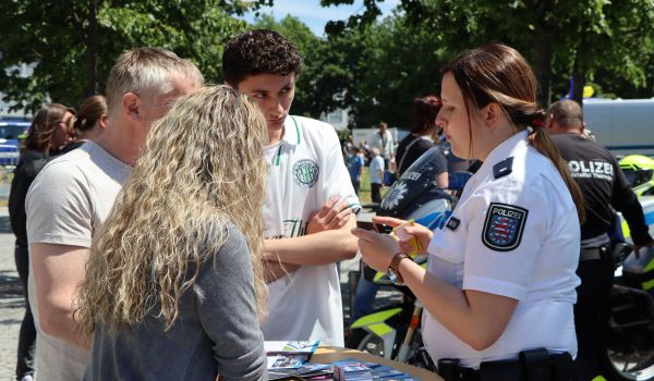Menschen stehen an einem Info-Stand der Polizei.