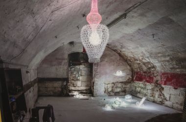 Beleuchtete Skulpturen aus Glas in einem alten Keller.