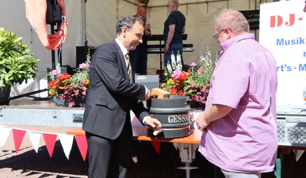 Ein Mann schlägt mit einem Hammer einen Zapfhahn in ein Bierfass. Es ist der 1. Beigeordnete Christian Dressel.