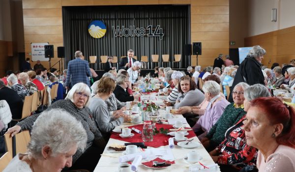 Frauen sitzen an gedeckten Kaffeetischen.