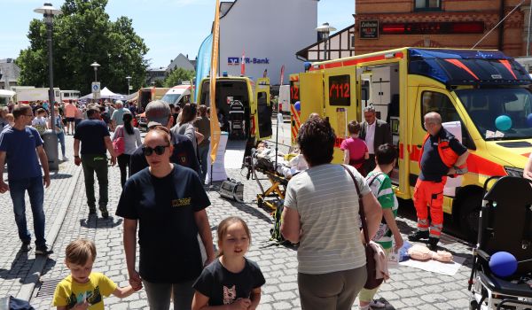 Zwei Krankenwägen stehen in der Innenstadt. Daneben laufen Menschen.