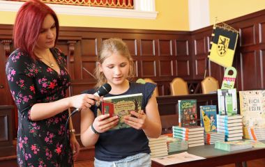 Ein Kind steht neben einer Frau und ließt die vor.