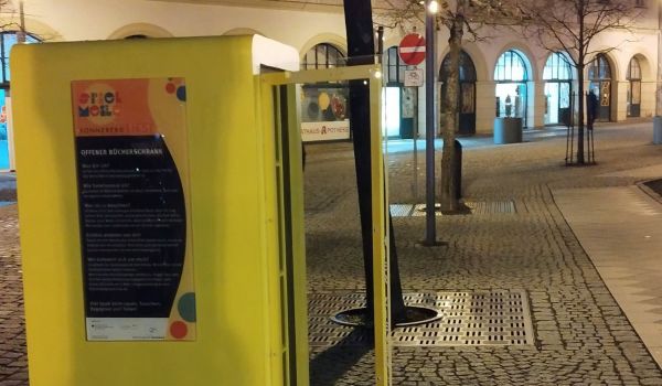 Ein gelber Bücherschrank steht am Bahnhofsplatz.